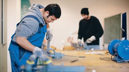 Der afghanische Flüchtling Sha Kah Ahmadi (l.) und der indischen Flüchtling Singh Satwinder feilen am 10.12.2015 in der Fortbildungsakademie der Wirtschaft (FAW) in Dresden (Saschen) an Metallwerkstücken.