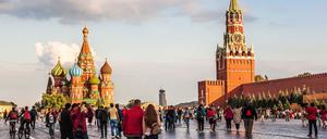 Menschen spazieren über den Roten Platz in Moskau. Links ist die Basilius-Kathedrale zu sehen, recht der Kreml.