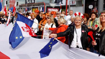 Demonstranten schwenken die EU-Flagge und die polnische Flagge, als sie sich am 1. Oktober 2023 im Zentrum Warschaus zu dem von der Opposition organisierten „Marsch der Millionen Herzen“ versammeln.