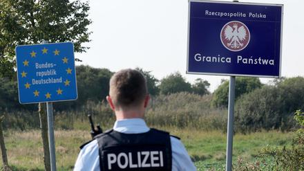 Bei einer flexiblen Schwerpunktkontrolle unmittelbar an der deutsch-polnischen Grenze in der Nähe des ehemaligen Grenzübergang Linken steht ein Bundespolizist vor den Schildern für Deutschland und Polen. 