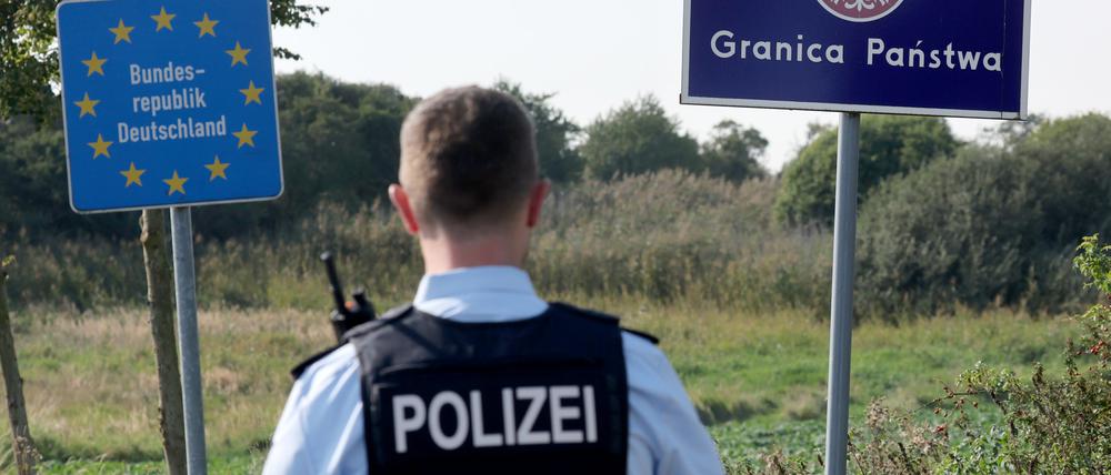 Bei einer flexiblen Schwerpunktkontrolle unmittelbar an der deutsch-polnischen Grenze in der Nähe des ehemaligen Grenzübergang Linken steht ein Bundespolizist vor den Schildern für Deutschland und Polen. 