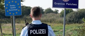 Bei einer flexiblen Schwerpunktkontrolle an der deutsch-polnischen Grenze steht ein Bundespolizist vor den Schildern für Deutschland und Polen. 