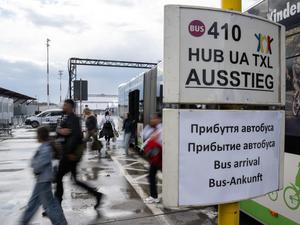 Menschen steigen aus dem BVG-Shuttel und gehen an Schildern mit Informationen auf Deutsch und Ukrainisch vorbei.