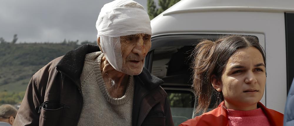 Ein verwundeter armenischer Mann namens Sasha, 84 Jahre alt aus Stepanakert in Bergkarabach, wird von Freiwilligen bei seiner Ankunft in der armenischen Stadt Goris in der Region Syunik, Armenien gestützt.