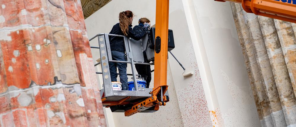 Mitarbeiter eines Restaurateurs überstreichen Farbflecken am Brandenburger Tor. Die letzte Generation hatte Mitte September bei einer Aktion das Brandenburger mit Farbe besprüht.