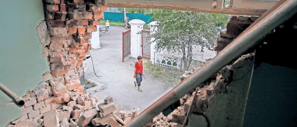 Ein zerstörtes Gemäuer gibt den Blick auf eine junge Ukrainerin frei.