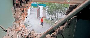 Ein zerstörtes Gemäuer gibt den Blick auf eine junge Ukrainerin frei.