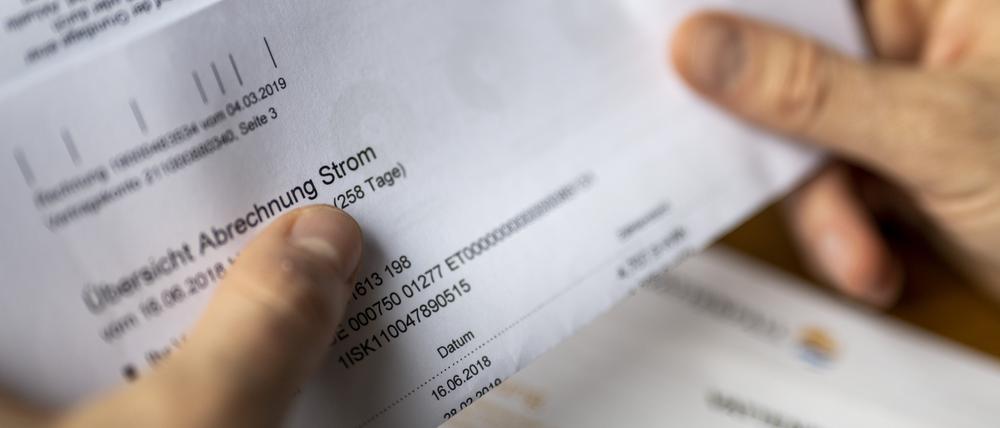 Ein Mann hält eine Stromrechnung in den Händen.