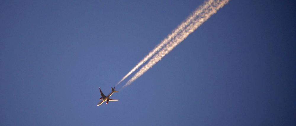 Flugzeug mit Kondensstreifen am blauen Himmel. 