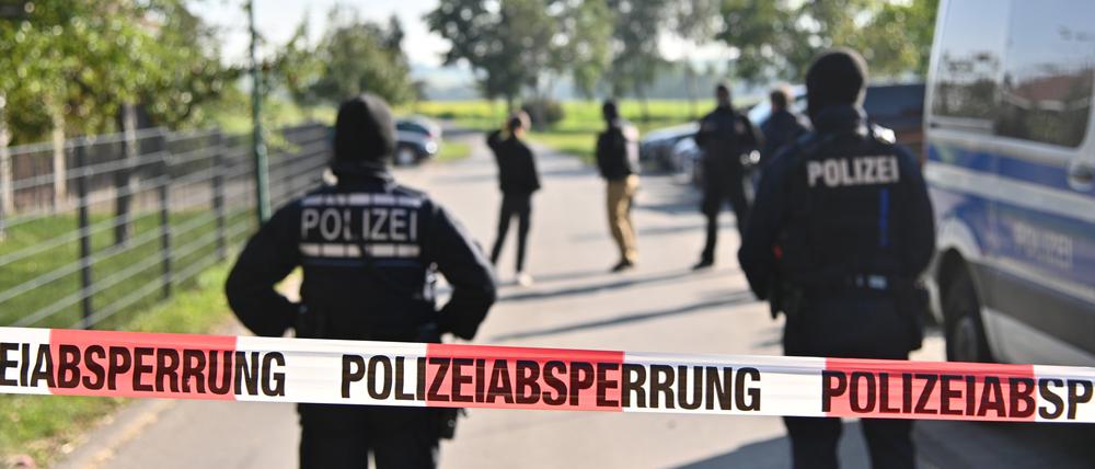 Einsatzkräfte der Polizei stehen hinter einer Polizeiabsperrung (Symbolbild)