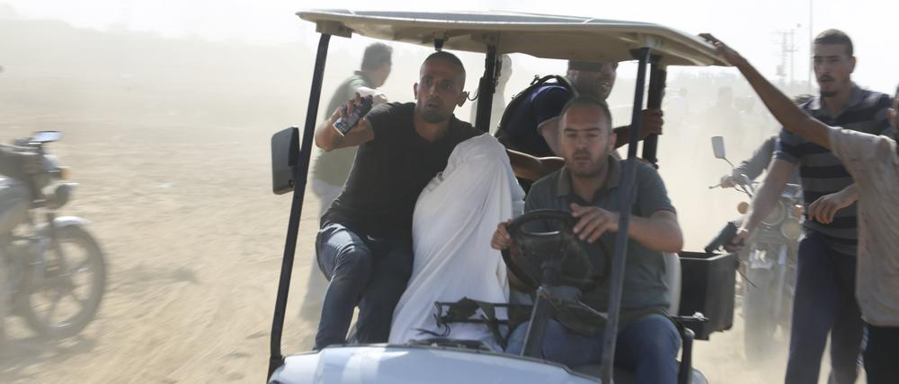 Palästinenser transportieren einen gefangenen israelischen Zivilisten aus dem Kfar Azza Kibbuz.