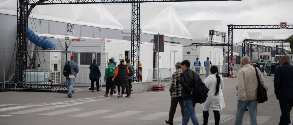 Bewohner und Mitarbeiter gehen im Ankunftszentrum am ehemaligen Flughafen Tegel in Richtung der Leichtbauhallen.