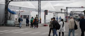 Bewohner und Mitarbeiter gehen im Ankunftszentrum am ehemaligen Flughafen Tegel in Richtung der Leichtbauhallen.
