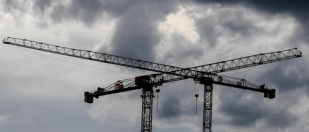 Baukräne sind vor dunklen Wolken zu sehen (Symbolbild).