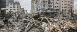 Palästinenser stehen inmitten zerstörter Gebäude in Gaza-Stadt.