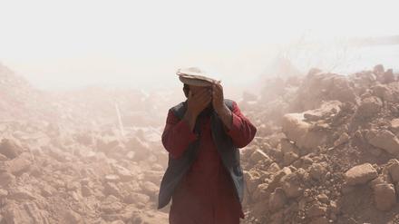 Ein Afghane bedeckt sein Gesicht, um sich vor dem Staub nach dem Erdbeben zu schützen.