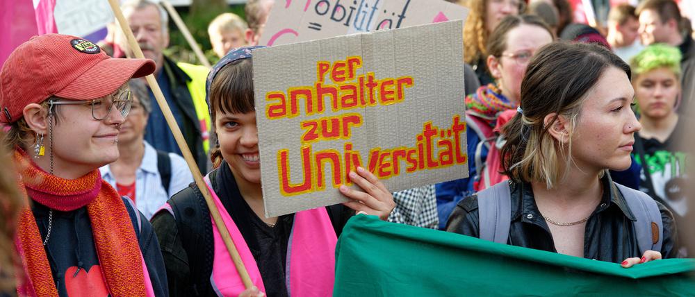 Teilnehmer einer Protestkundgebung vor der Verkehrsministerkonferenz (VMK) halten Plakate.