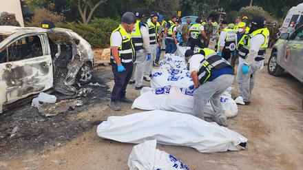 Dieses vom Rettungsdienst Zaka zur Verfügung gestellte Foto zeigt Mitarbeiter des Rettungsdiensts Zaka neben Leichensäcken und verbannten Autos in einem Kibbuz im Süden Israels nach dem Massaker der islamistischen Hamas. 