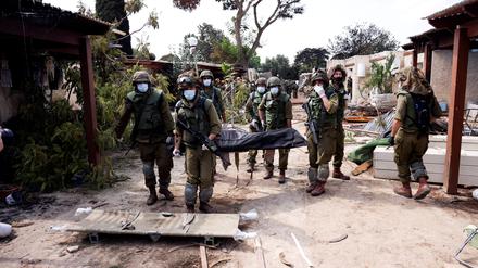 Israelische Soldaten tragen im Kibbuz Kfar Aza nach dem Massaker der Hamas eine Leiche weg.