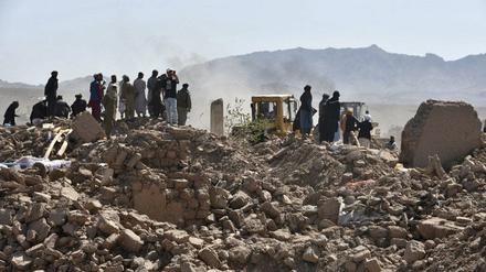 Überlebende des Erdbebens in Afghanistan stehen neben den Resten von zerstörten Häusern. 