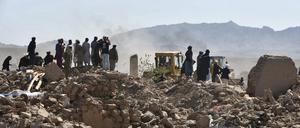 Überlebende des Erdbebens in Afghanistan stehen neben den Resten von zerstörten Häusern. 