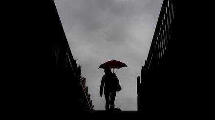 Eine Frau steigt waehrend eines Regenschauers die Treppen aus der U-Bahn-Station Franzoesische Strasse in Berlin hinauf. (Symbolbild)