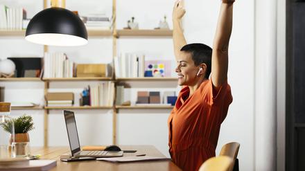 Eine Mitarbeiterin im Homeoffice freut sich über ihren Feierabend.