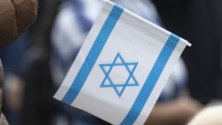Ein Teilnehmer einer Kundgebung im Zentrum der Stadt hält eine Kerze und eine israelische Fahne in seiner Hand.