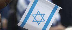 Ein Teilnehmer einer Kundgebung im Zentrum der Stadt hält eine Kerze und eine israelische Fahne in seiner Hand. 