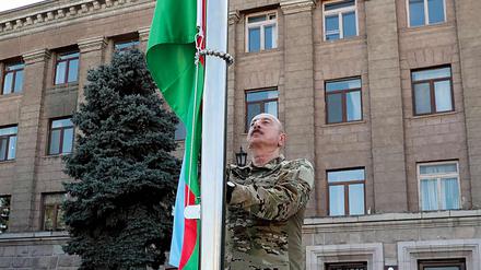 Der aserbaidschanische Präsidenten Ilham Aliyev hisst bei seinem Besuch in der Hauptstadt Bergkarabachs die aserbaidschanische Nationalflagge.