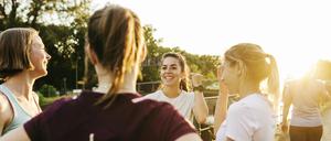 A female fitness group chatting by a canal before beginning a run through the city together.