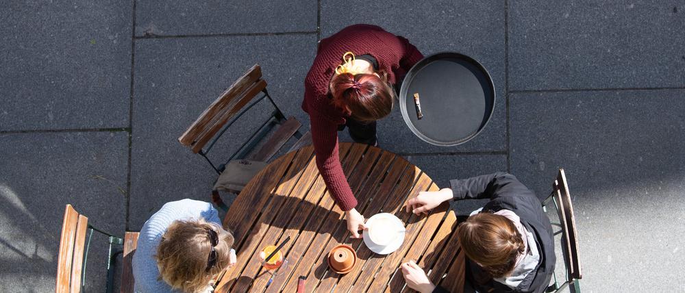 ARCHIV - 15.05.2020, Sachsen, Dresden: Eine Kellnerin bedient in einem Cafe zwei Frauen. Jeder vierte sozialversicherungspflichtig Beschäftigte im Gastgewerbe hat der Branche während der Pandemie den Rücken gekehrt - bei der Rückgewinnung von Personal kommen die Betriebe einer Untersuchung zufolge nur langsam voran.  (Zu dpa "Studie zu Gastgewerbe: Jeder vierte Beschäftigte ist gegangen") Foto: Sebastian Kahnert/dpa-Zentralbild/dpa +++ dpa-Bildfunk +++