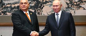Der ungarische Ministerpräsident Viktor Orbán und der russische Präsident Wladimir Putin schütteln die Hand vor ihrem Treffen in Peking. 