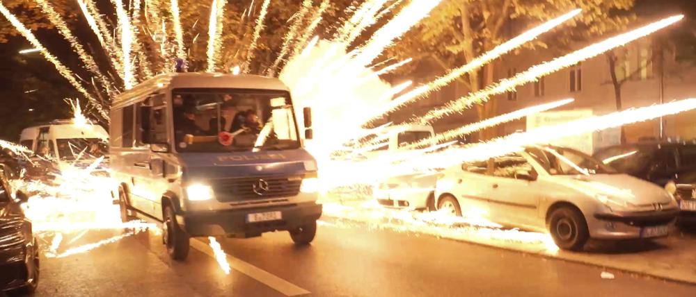 Feuerwerkskörper fliegen hinter einem Polizeiauto bei einer nicht angekündigten pro-palästinensischen Demonstration in Neukölln.
