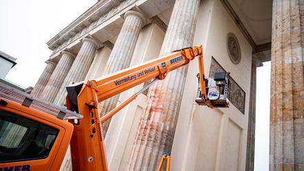 05.10.2023, Berlin: Mitarbeiter eines Restaurateurs überstreichen Farbflecken einer früheren Protestaktion der "Letzte Generation" am Brandenburger Tor. Foto: Fabian Sommer/dpa +++ dpa-Bildfunk +++