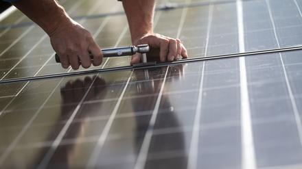 ARCHIV - 13.10.2021, Baden-Württemberg, Stuttgart: Mitarbeiter einer Firma montieren Photovoltaikmodule auf dem Dach eines Wohnhauses. (zu dpa: «Batteriespeicher in neuen EnBW-Solarparks werden Standard») Foto: Marijan Murat/dpa +++ dpa-Bildfunk +++
