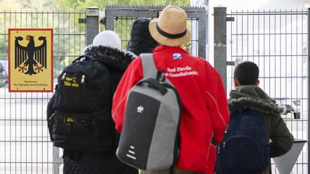 Geflüchtete betreten neben einem Schild vom Bundesamt für Migration und Flüchtlinge die Landesaufnahmebehörde Niedersachsen am Standort Braunschweig.