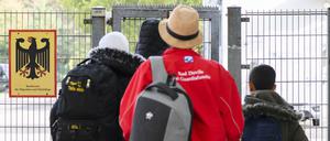 Geflüchtete betreten neben einem Schild vom Bundesamt für Migration und Flüchtlinge die Landesaufnahmebehörde Niedersachsen am Standort Braunschweig. 