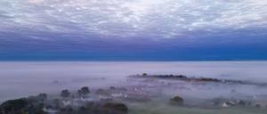 Der kleine Ort Petersdorf im Landkreis Oder-Spree ist am frühen Morgen von Nebelschwaden eingehüllt (Luftaufnahme mit einer Drohne).