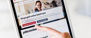 Eine Frau tippt auf einem Tablet auf einen Link zum Beantragen des Bürgergeldes im Kundenbereich im Jobcenter Berlin Mitte.