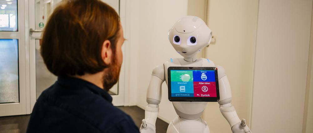 Robert Ranisch, Juniorprofessor für Medizinische Ethik mit Schwerpunkt auf Digitalisierung an der Fakultät für Gesundheitswissenschaften der Universität Potsdam, mit einem Pflegeroboter.