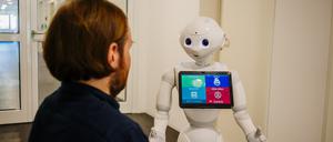 Robert Ranisch, Juniorprofessor für Medizinische Ethik mit Schwerpunkt auf Digitalisierung an der Fakultät für Gesundheitswissenschaften der Universität Potsdam, mit einem Pflegeroboter.