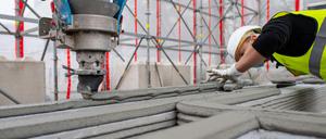 Ein Mitarbeiter eines Bauunternehmens beobachtet einen 3D-Drucker, der die nächste Schicht Beton auf Wände aufträgt. (Archivfoto) 
