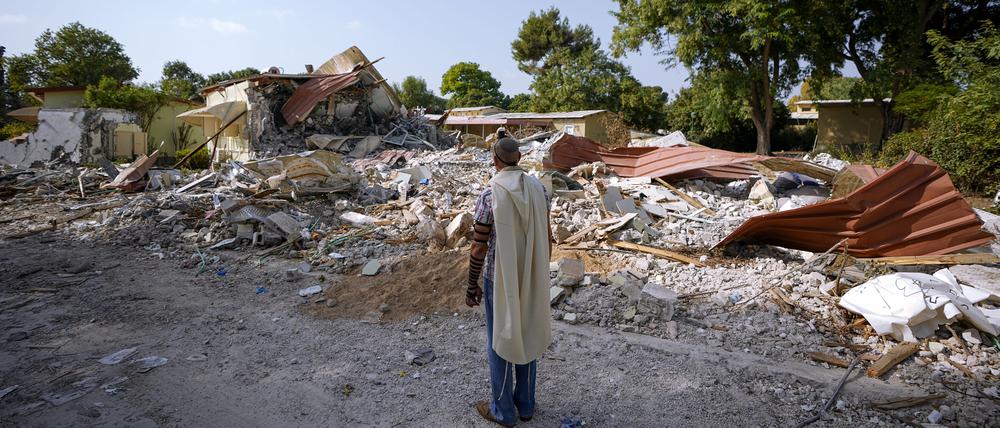 Ein israelischer Mann, der einen Gebetsschal trägt, betet neben Häusern, die durch die Hamas zerstört wurden.