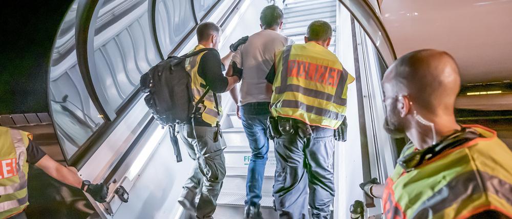 Polizeibeamte begleiten einen ausreisepflichtigen Afghanen auf dem Flughafen Leipzig-Halle in ein Charterflugzeug