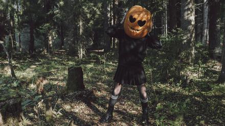 Woman wearing carved Jack O Lantern and standing in forest model released, Symbolfoto, VBUF00448 Kürbis Tanz Halloween