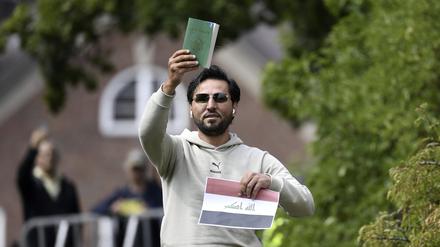 Salwan M.  hält eine Kopie des Korans, die er mutmaßlich gemeinsam mit einer irakischen Fahne vor der irakischen Botschaft in Stockholm verbrennen will.