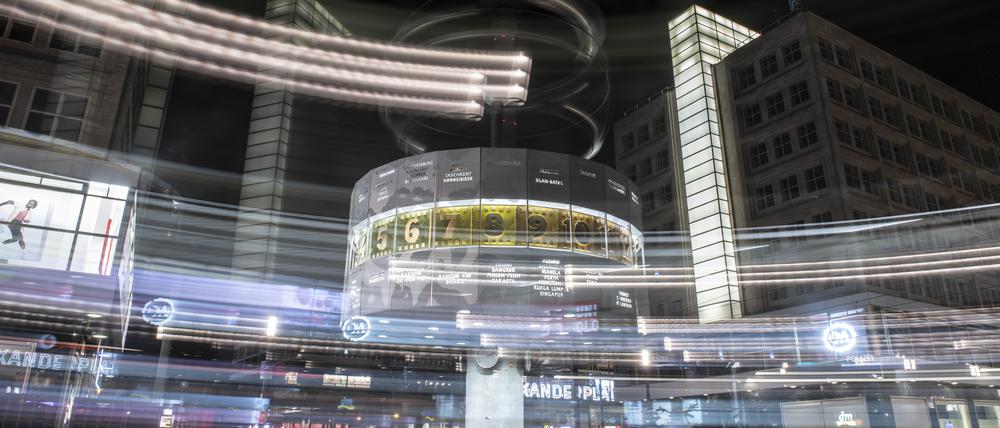 Bunte Lichtstreifen rahmen die Weltzeituhr auf dem Alexanderplatz in der Nacht ein.