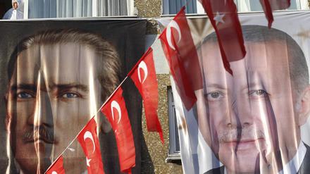 Eine Frau blickt aus einem Fenster hinter einem Banner des türkischen Staatsgründers Atatürk (l) und des türkischen Präsidenten Erdogan.