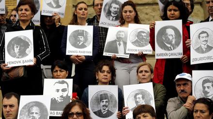 Türkische und armenische Bürger halten Bilder von getöteten armenischen Völkermordopfern.